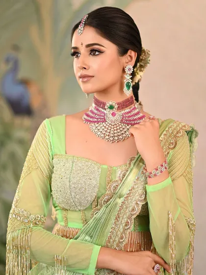 A stunning portrait in a light green saree, showcasing a modern take on ethnic wear. The focus is on the intricate blouse design and the elegant jewelry, perfect for a sangeet or reception look.