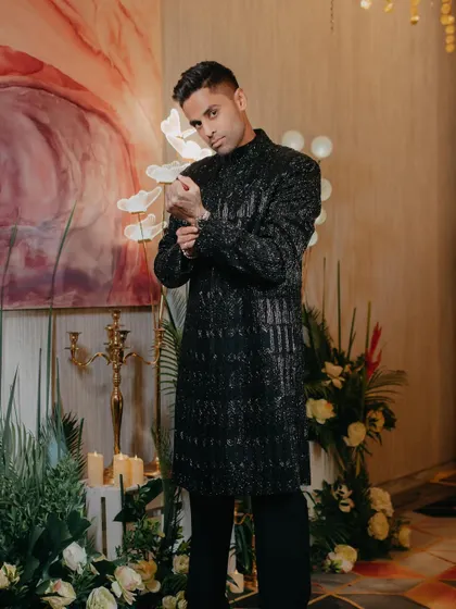 Suryakumar Yadav in a glittering black sherwani by Manish Malhotra. This is the perfect look for a glamorous evening event, designed to catch the light and make a statement.