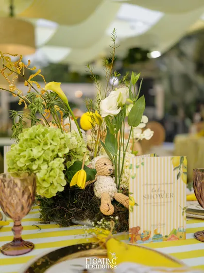 A close-up of the beautiful tablescape. We used yellow and white striped linens, vintage-style colored glassware, and lush floral centerpieces to create a cheerful and elegant dining experience for the baby shower guests.