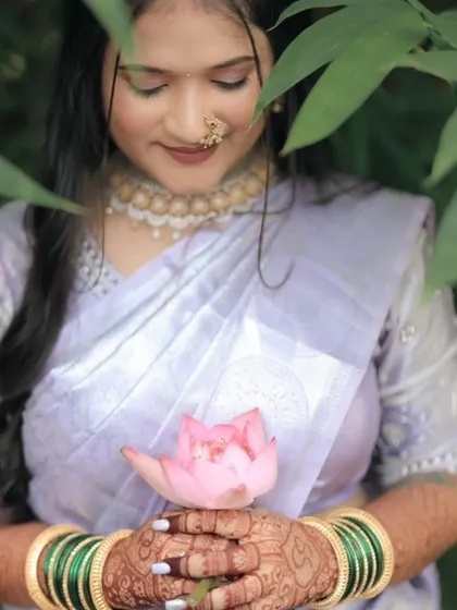 A close-up of the bride's hands holding a lotus flower, showcasing her intricate engagement mehndi. The design is as beautiful as the flower she holds.