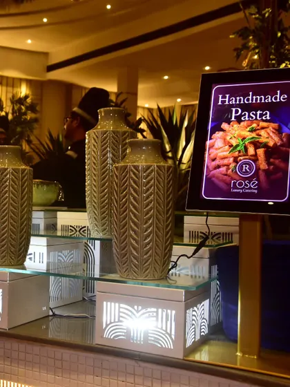 An elegant setup for our handmade pasta station, featuring decorative vases and illuminated display boxes. The presentation is designed to be as refined and appealing as the food itself.