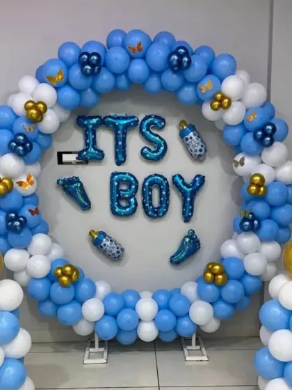 A bright and cheerful "It's a Boy" balloon ring. The blue and white balloons are accented with gold clusters and baby-themed foil balloons, creating a perfect photo spot.