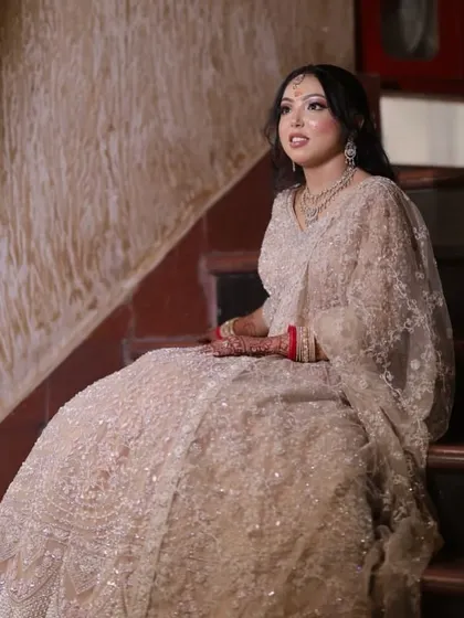 The bride seated on the stairs, looking like a princess in her elaborate engagement lehenga.