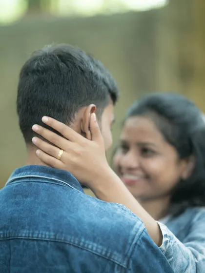 An over-the-shoulder shot focusing on the bride-to-be's hand gently caressing her partner's face, capturing a tender and intimate pre-wedding moment.