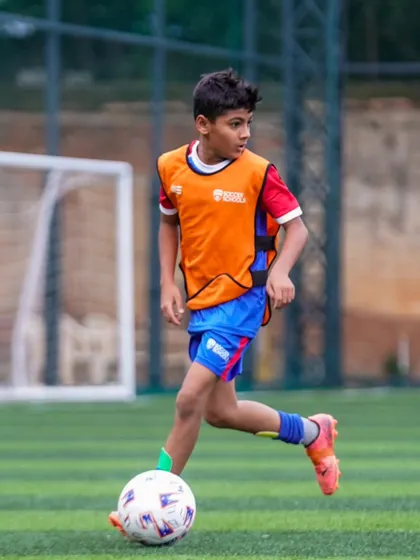 A player in an orange bib scans the pitch for options. Our training encourages intelligent play and decision-making.