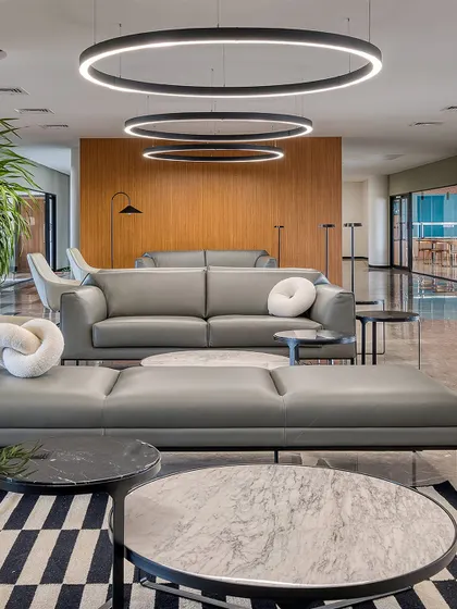 The waiting lounge at Laurus Labs, featuring modern grey sofas and circular pendant lights. We designed this space to be comfortable and sophisticated, using a clean material palette of wood and marble.