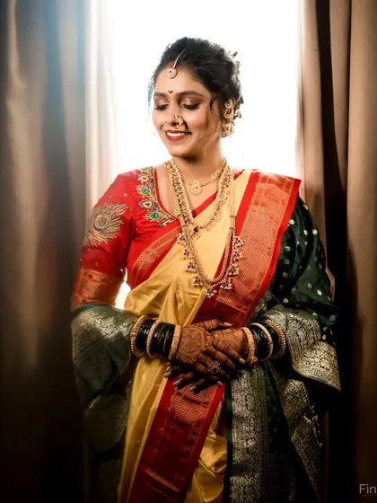 A shy, happy smile from the bride, captured in soft, flattering light. This portrait showcases her complete traditional look, from the jewelry to the beautiful saree.