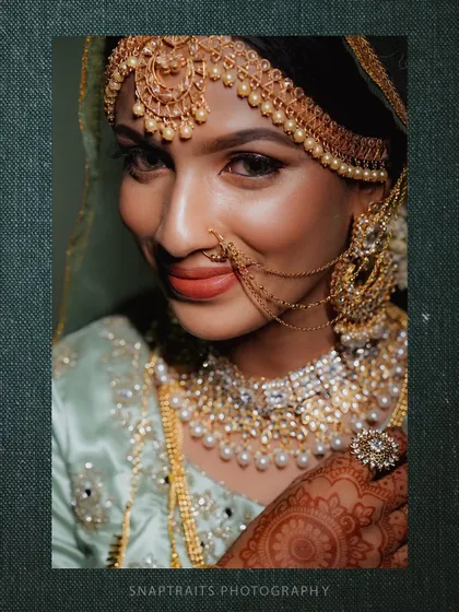 A close-up portrait of the bride, her eyes sparkling and her intricate jewelry on full display.
