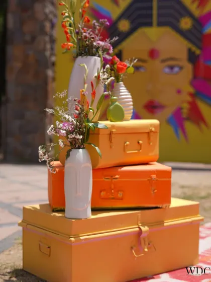 It's all in the details. We used stacked, brightly painted vintage trunks and unique face-themed vases to create interesting decor corners that added to the quirky and colorful theme of the Haldi event.