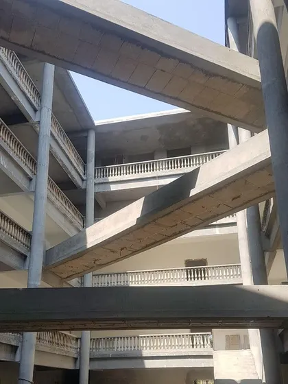The raw concrete structure of the bridging system in a Nursing College, seen here under construction. The image reveals the complex engineering required to create the crisscrossing circulation paths.