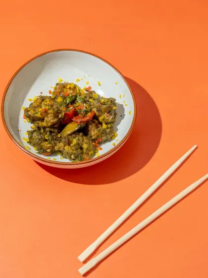A minimalist composition using a bold, orange background to make the Asian-style dish pop. This modern approach to food photography is designed to grab attention on a busy social media feed.