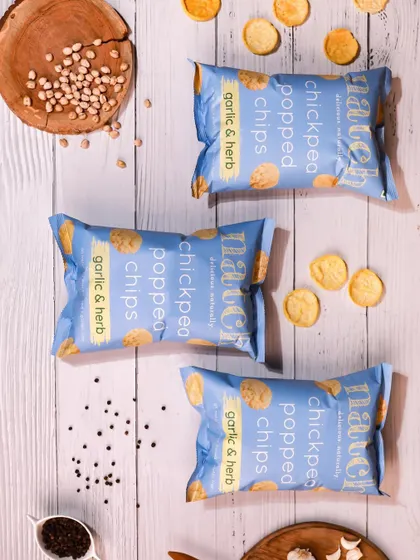 A rustic flatlay for garlic & herb chips on a white wooden background. This styling gives a natural and wholesome feel to the product.