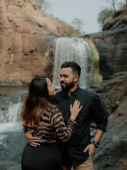 A close-up, loving gaze between the couple, with the soft cascade of the waterfall behind them.