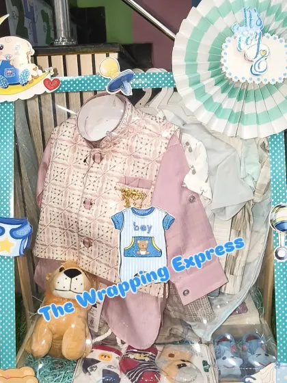 A welcome baby hamper for a boy, including a traditional jacket and kurta set, along with a teddy bear and other essentials.