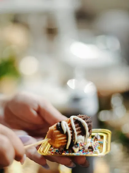 A guest enjoys a custom-made churro from our live dessert counter. Our interactive stations allow guests to personalize their treats with various toppings and sauces.