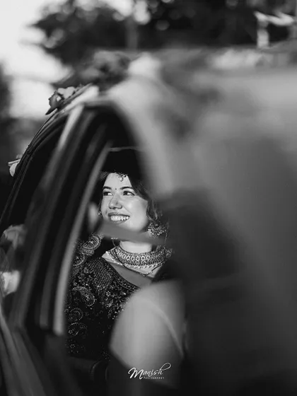 A candid black and white shot of the bride's happy smile as she leaves after the wedding, a beautiful end to one chapter and the start of another.