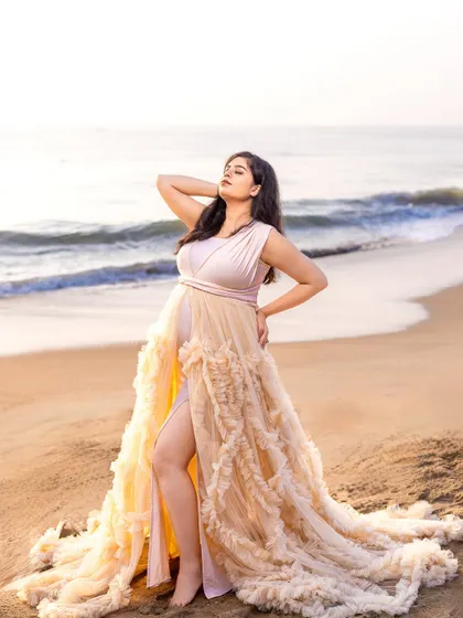 A portrait of pure elegance. The mom-to-be stands gracefully on the shore, her gown spread out around her like a work of art.