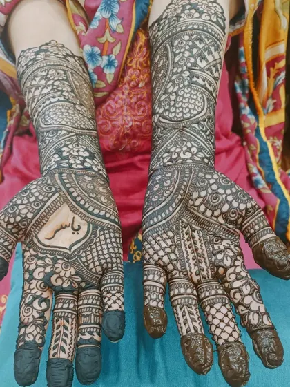 This full-coverage design has a personal touch, with the name 'Yasir' elegantly written in the center of the palm. The dark, fresh henna paste ensures the name will be a prominent feature as the stain develops.