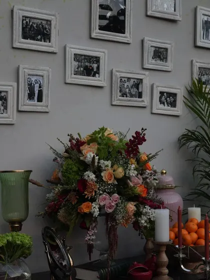 A memory wall I created, featuring a collection of the couple's family photos in distressed white frames, surrounded by beautiful floral arrangements.
