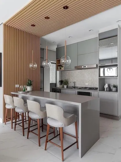 A minimalist grey kitchen with a large, simple island that provides ample counter space and seating. The design is perfect for open-concept living and entertaining.