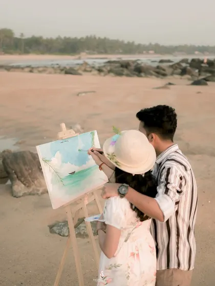 A close-up of the couple painting together on the beach. This shot focuses on the collaborative and creative aspect of their relationship.