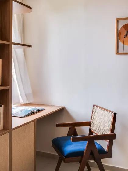 Another angle of the study area, showing the classic Pierre Jeanneret-inspired cane chair in a striking blue, adding a pop of color to the neutral space.