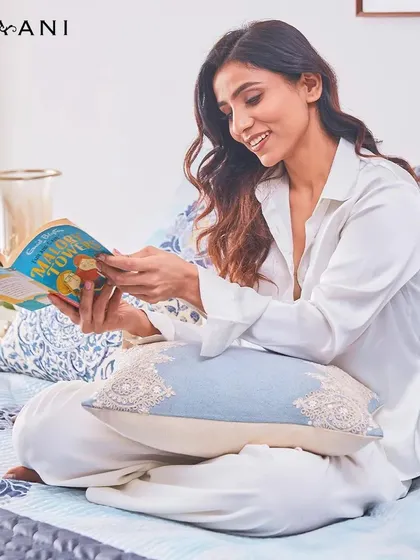It's in moments like these that you understand the calming effect of blue. A woman enjoys a book, surrounded by the serene patterns of my Indigo collection, soothing the soul with timeless beauty.