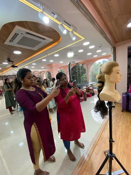 Students eagerly capturing the final result of a hairstyling demo.