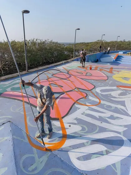 Using a long roller to outline letters on the ground at the skatepark. For massive pieces, you have to get creative with your tools.