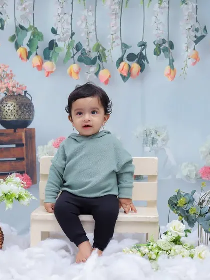 This little one looks calm and curious in our cloud and flower-themed studio set. We create serene environments to capture beautiful, peaceful portraits.