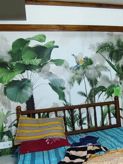 Here, a vibrant jungle scene wallpaper is framed by dark wood, turning the wall behind the bed into a beautiful, art-like feature in this Vasai home.