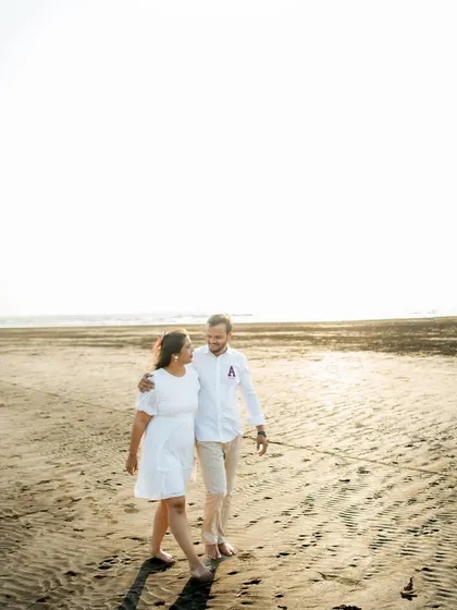 A candid shot of a couple walking along a sandy beach. This pre-wedding photo captures a natural, unposed moment of conversation and connection.