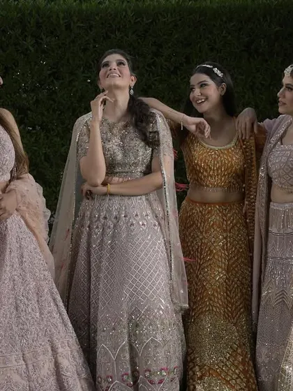 A candid moment between friends, all dressed in our gorgeous pastel and golden lehengas. This image captures the joy and camaraderie of a wedding celebration.