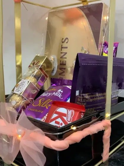 This image captures the rich assortment of chocolates inside the metal bow hamper, making it a truly indulgent gift.