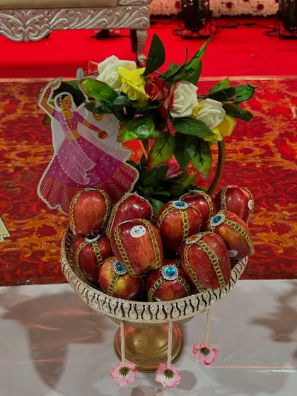 A platter of shiny red apples, each decorated with a beautiful stone-studded sticker. This simple idea adds a touch of sparkle and makes the fruit offering look very rich.