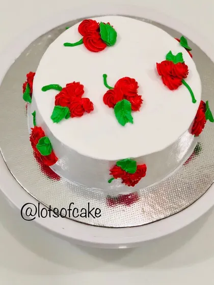 A simple and elegant design using whipped cream. In my workshops, I teach easy piping techniques to create beautiful patterns like these red rosettes on a classic white cake.
