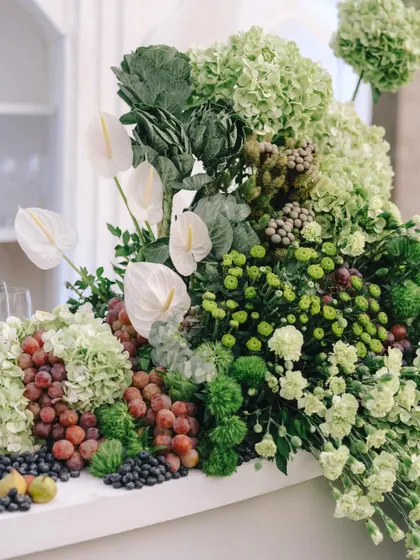 A stunning bar arrangement featuring a cascade of green hydrangeas, white anthuriums, grapes, and figs.