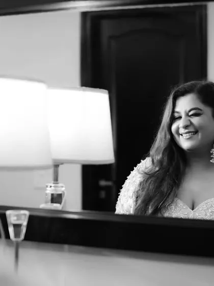 A candid moment of happiness reflected in the mirror. This black and white shot captures the bride's genuine smile while getting ready for her big day.