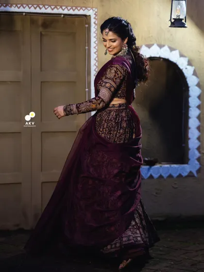 A full-length shot showing the unique draping of the Kalamkari lehenga. The hairstyle is a modern, textured braid that complements the traditional attire.