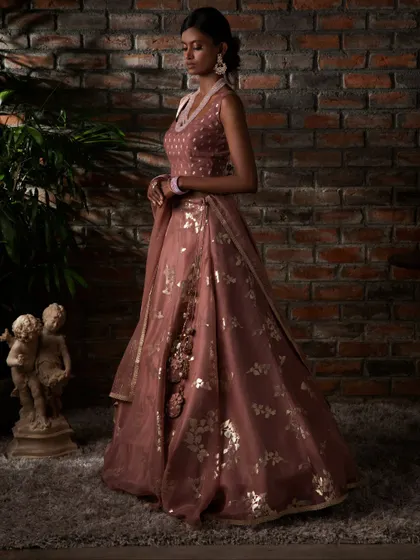 A side profile of the dusty rose lehenga, highlighting the delicate floral motifs and the flowing organza fabric, perfect for a sophisticated celebration.