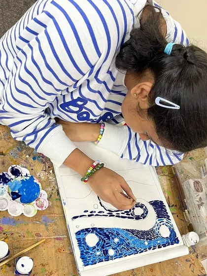 A young student works on her painting, demonstrating the focus and determination that art helps to build.