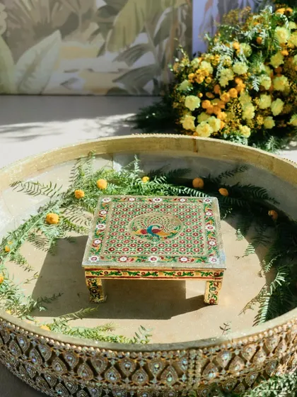 A hand-painted 'bajot' or low stool, featuring a peacock design, ready for the Haldi ceremony in Marrakech.