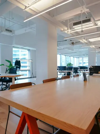 A view of a large communal work table, designed to encourage teamwork and flexible working arrangements within the open office.
