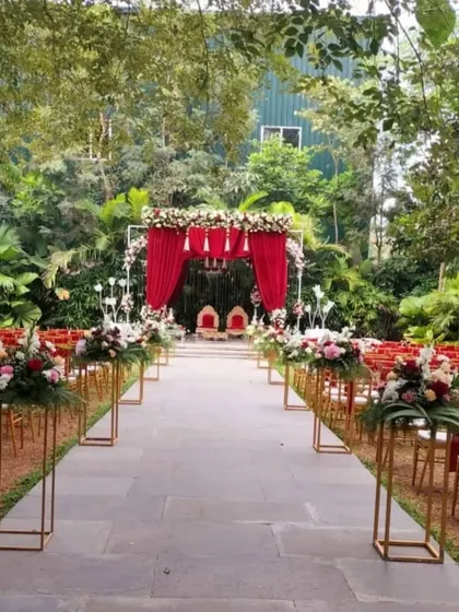 We design the entire ceremony space to be cohesive and beautiful. This wide-angle view shows the red-themed mandap and aisle, lined with floral pedestals, creating a dramatic and elegant path for the couple.