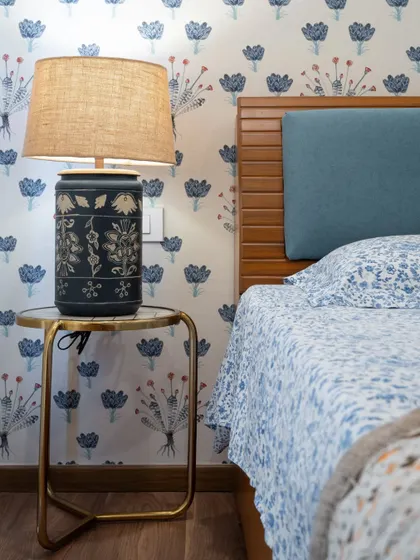 A close-up of the bedside table, featuring a beautiful ceramic lamp with intricate carvings that complements the traditional Indian aesthetic of the room.