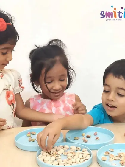 Children shell pistachios and grind nuts with a mortar and pestle to prepare a healthy date dessert for Eid. These activities develop fine motor skills and introduce them to different food textures.