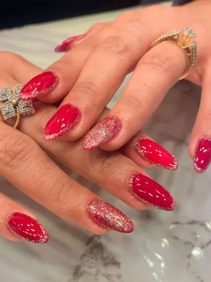 A vibrant and fiery look with almond-shaped nails. This set features bright red nails with a fine red glitter outline and full-coverage pink glitter accent nails.