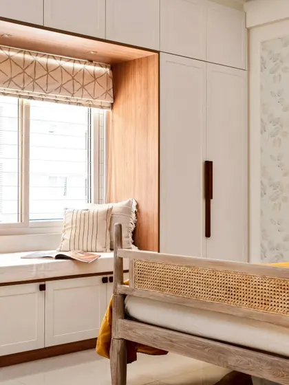 Another view of the guest bedroom, showing the four-poster bed with a cane headboard and the cozy bay window seating built into the wardrobe unit.