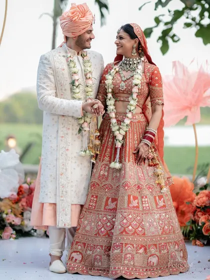 A beautiful portrait of the bride and groom after their Varmala, standing together and smiling, showcasing their stunning wedding outfits.