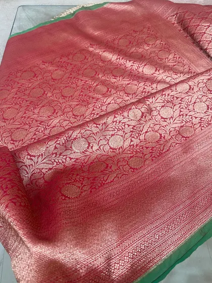Here is the full view of a red Banarasi silk saree with a green border. The pallu is covered in a dense floral jaal weave.